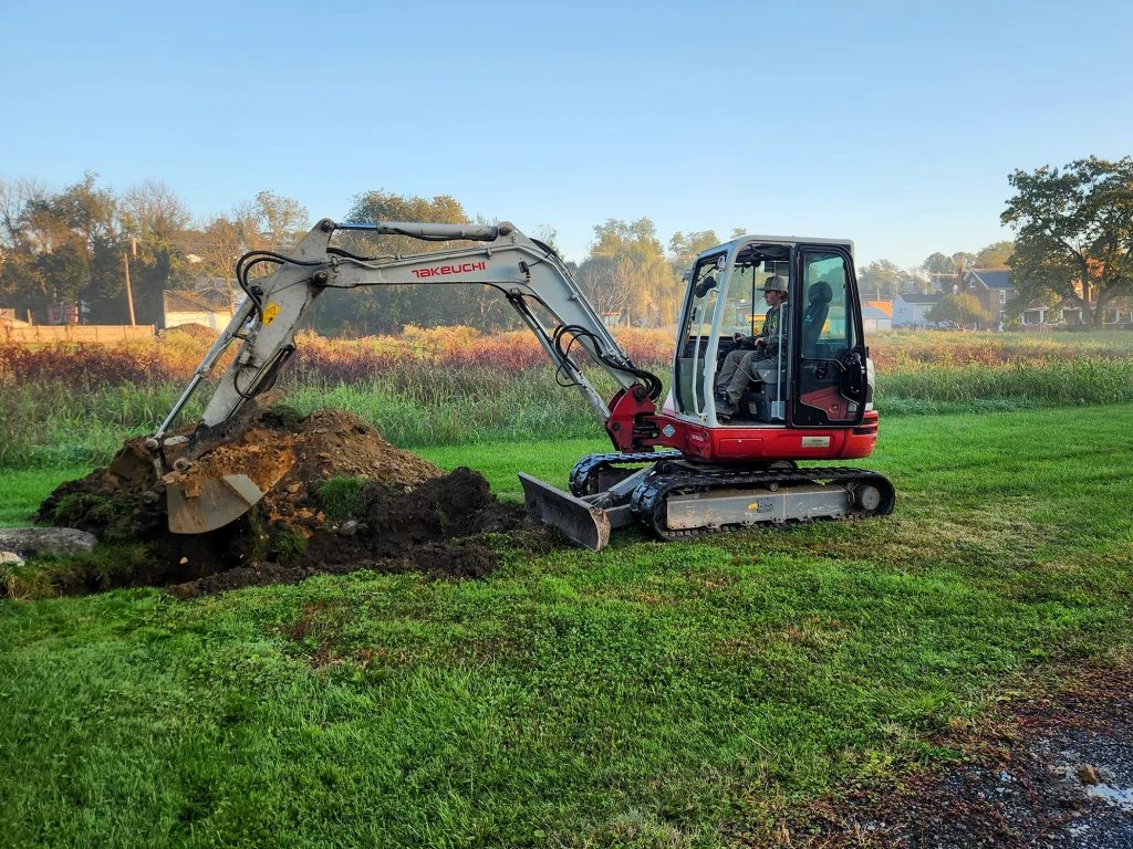 Excavator digging a soil test pit to evaluate ground conditions for stormwater infiltration.