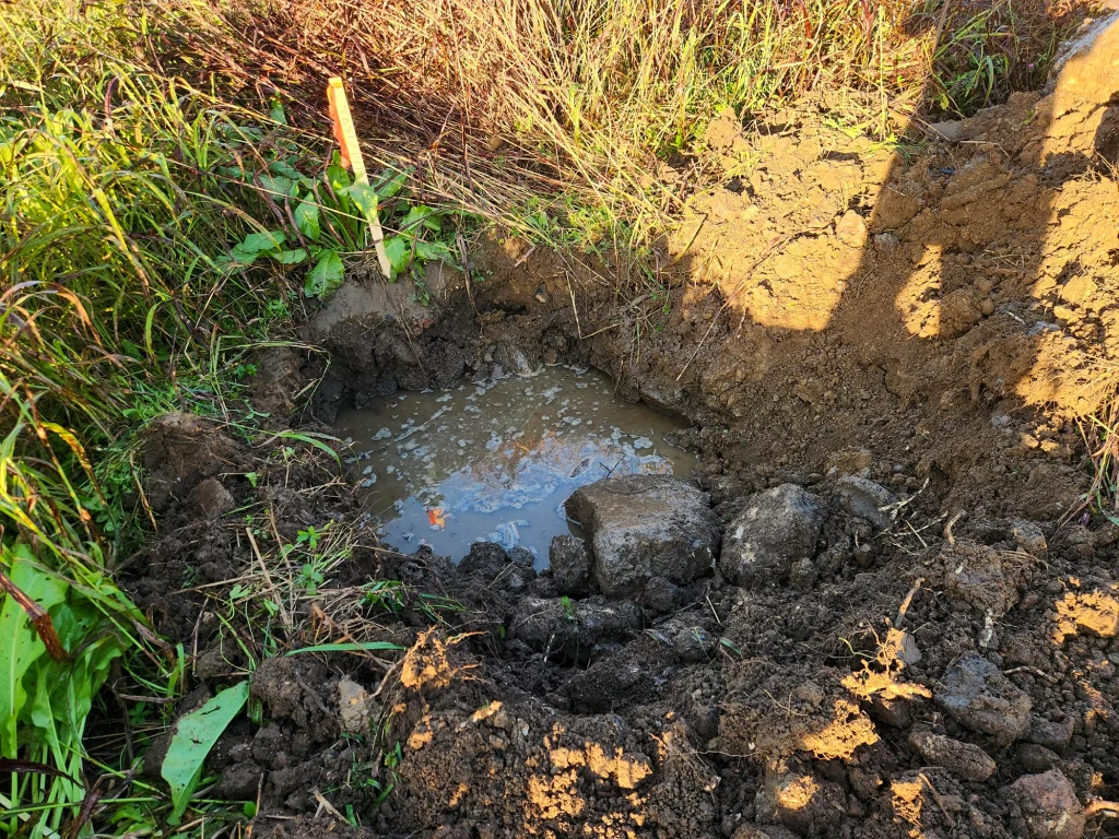 Soil test pit excavation for stormwater infiltration testing at a land development site.